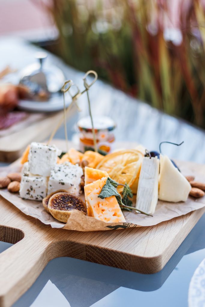 Delicious gourmet cheese platter featuring a variety of cheeses and fresh fruits on a wooden board.