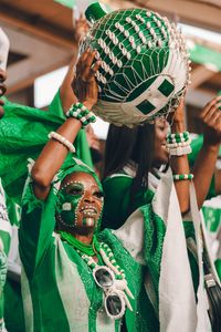 Joyful Nigerian fans celebrate in traditional attire with colorful face paint and cultural pride.