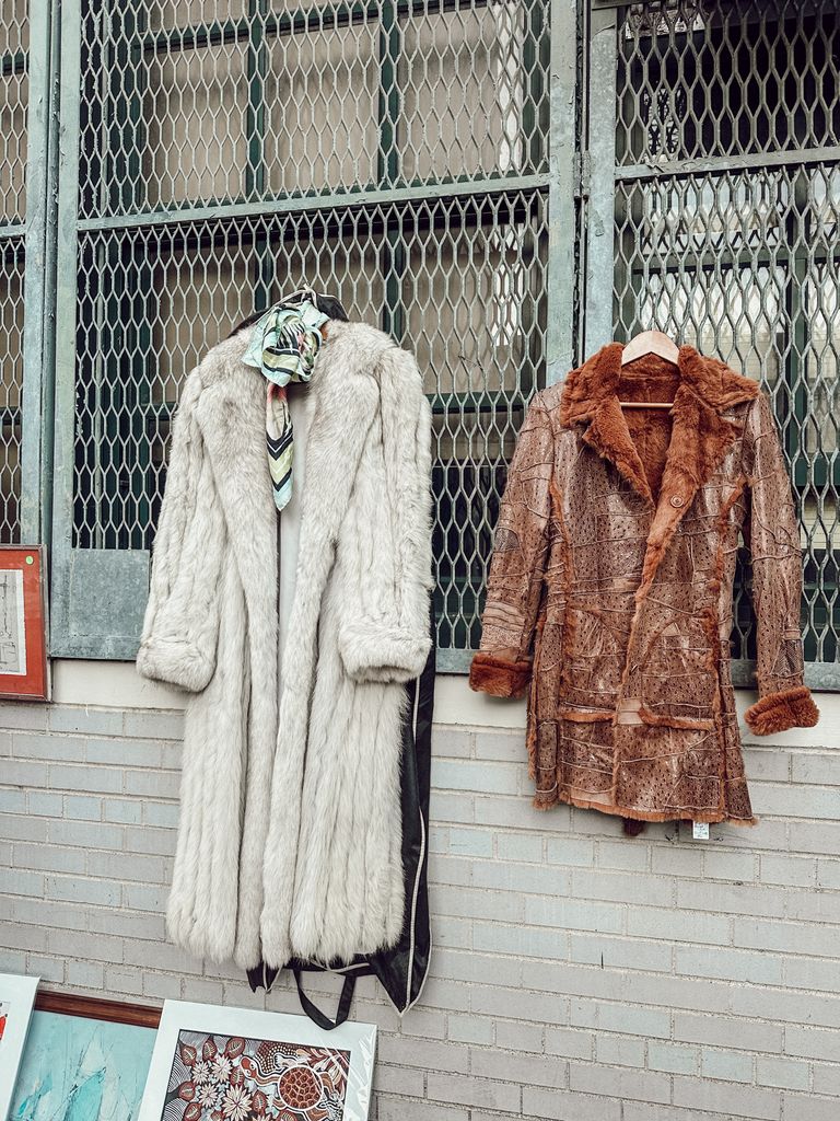 Retro fur coats hanging at an urban flea market in New York, showcasing vintage style.