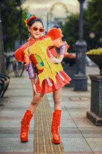 Vibrant fashionista poses in playful outfit on Bandung street, showcasing bold style.